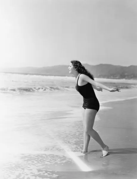 Vrouw lopen in het water op het strand — Stockfoto
