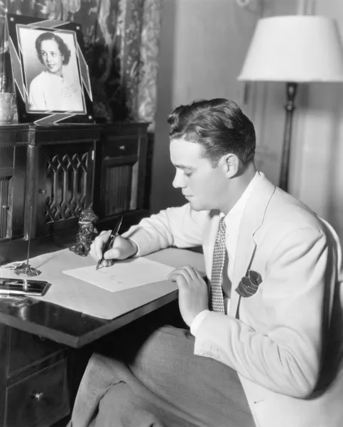 Uomo seduto alla scrivania a scrivere una lettera con una penna stilografica — Foto Stock