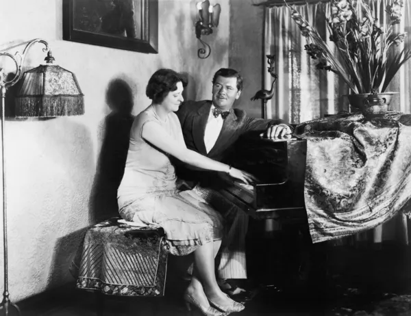 ピアノを弾く女性と一緒に座っている男 — ストック写真