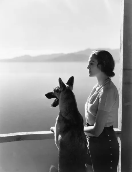 Mujer y su pastor alemán con vistas a un lago — Foto de Stock