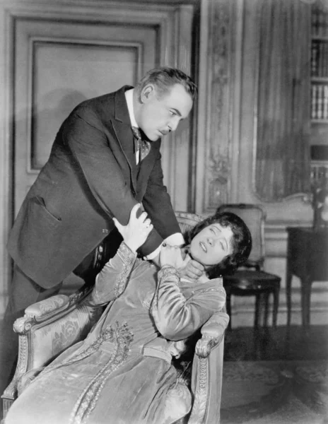 Άνθρωπος που στραγγαλίζει μια γυναίκα σε ένα καθιστικό — Φωτογραφία Αρχείου
