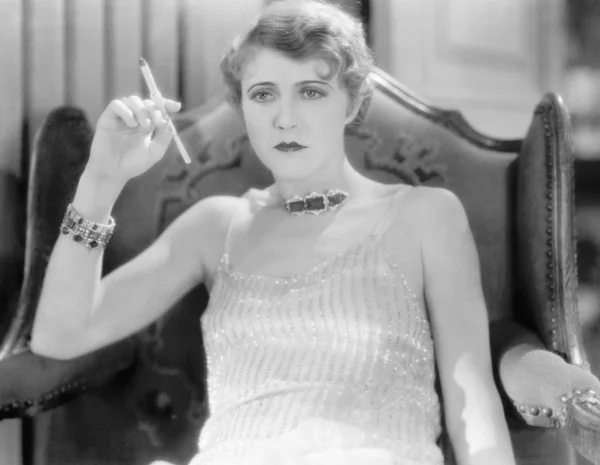 Mulher elegante em um vestido de noite e jóias fumando um cigarro — Fotografia de Stock