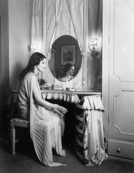 Mujer sentada en su mesa de vanidad — Foto de Stock