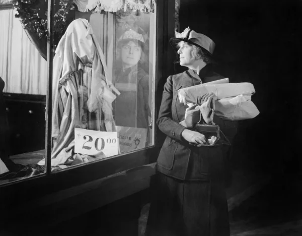 Jovem mulher olhando para uma janela de exibição ao chegar em sua bolsa — Fotografia de Stock
