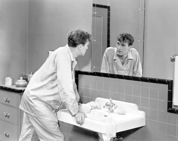 Mann im Badezimmer blickt in Spiegel — Stockfoto