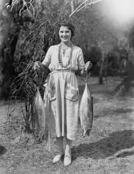 Mujer joven sosteniendo dos peces enormes —  Fotos de Stock