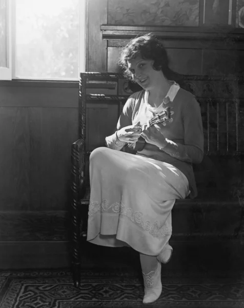 Fiatal nő ül egy padon, mandolinon játszik — Stock Fotó