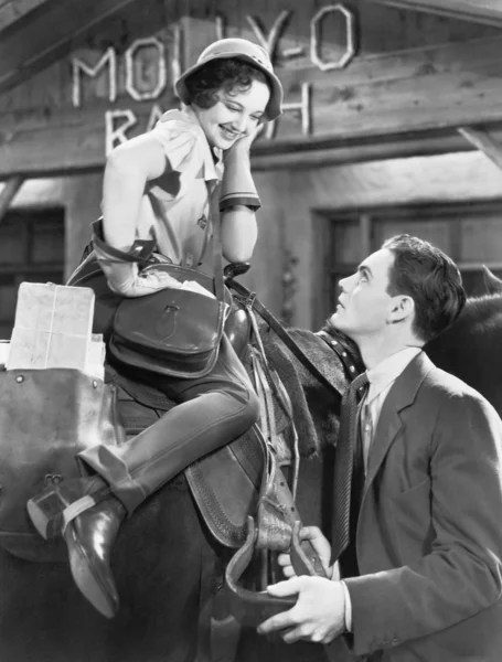 Mulher sentada em um cavalo conversando e flertando com um jovem — Fotografia de Stock