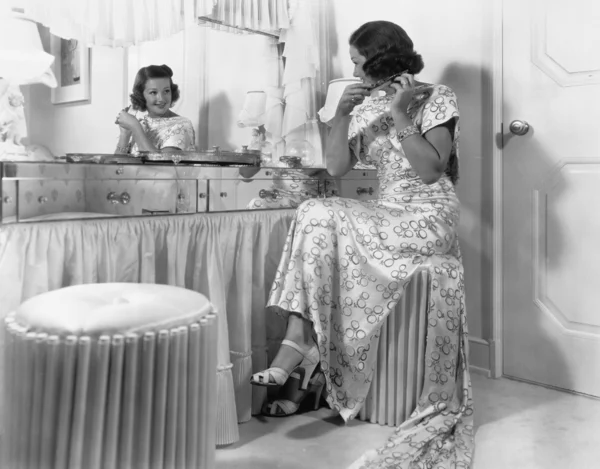 Mujer joven sentada frente a su vanidad peinándose —  Fotos de Stock