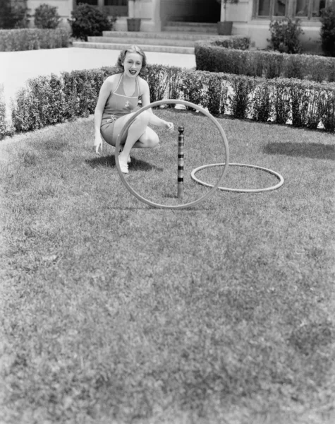 Молодая женщина в солнечном костюме играет с кольцами во дворе — стоковое фото