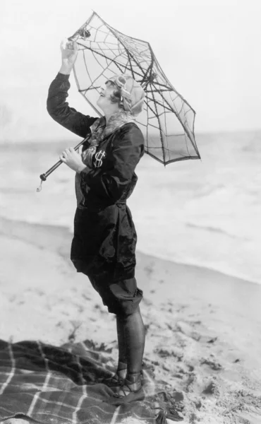 Junge Frau am Strand mit einem Schirm, der aussieht wie ein Spinnennetz — Stockfoto