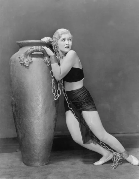 Mujer joven en vestido vestido encadenado a una urna buscando angustiado — Foto de Stock