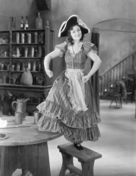 Ung kvinna med en buccaneer hatt dans på en stol — Stockfoto