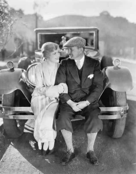 Casal sentado juntos em um pára-choques de carro — Fotografia de Stock