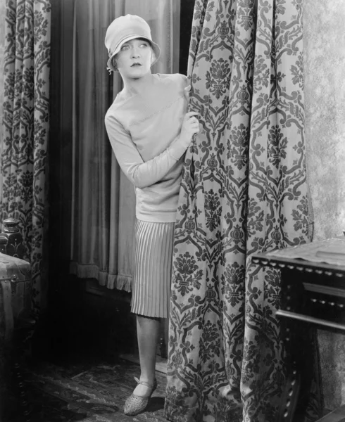 Jovem mulher olhando surpreso atrás de uma cortina — Fotografia de Stock