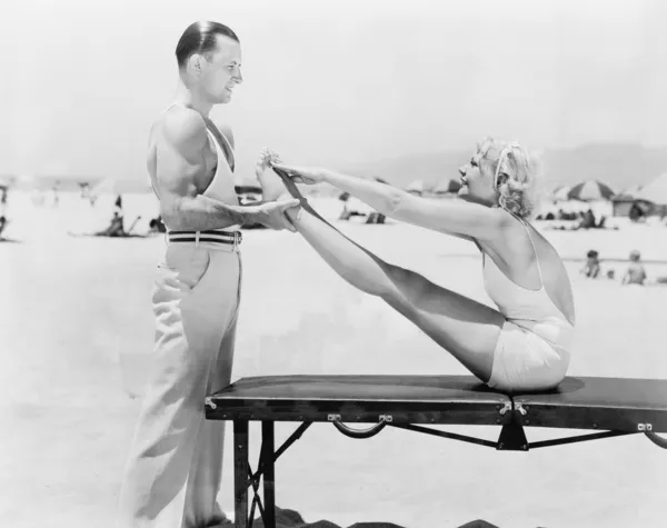 Allenatore e giovane donna che fanno esercizi in spiaggia — Foto Stock