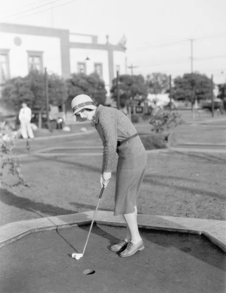 Jovem mulher jogando mini golfe — Fotografia de Stock