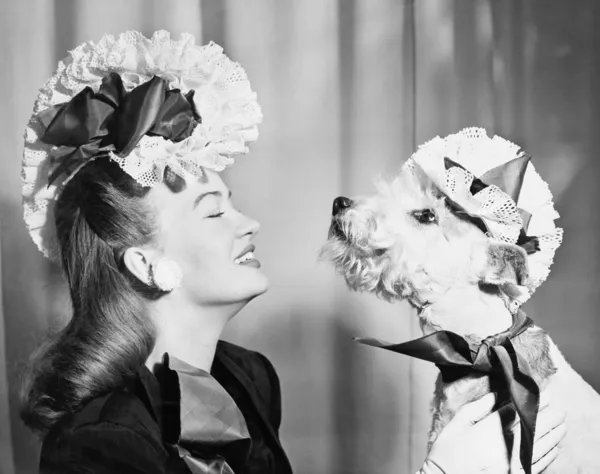 stock image Young woman with her dog who is wearing the same hat