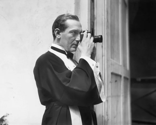 Hombre sosteniendo y mirando a través de una cámara —  Fotos de Stock