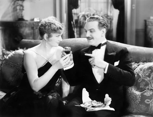 Casal sentado juntos em um sofá e tomando uma bebida — Fotografia de Stock