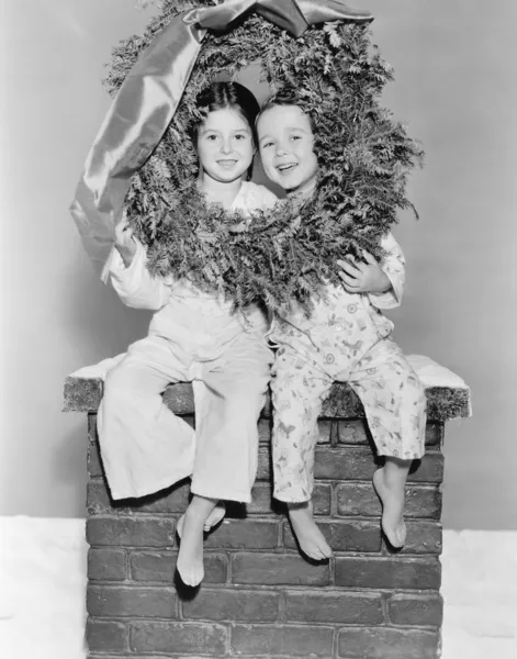 Hermano y hermana sentados en una chimenea — Foto de Stock