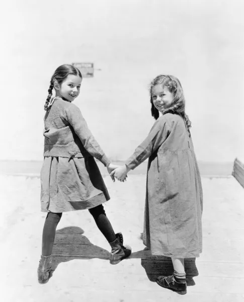 Två flickvänner promenader och hålla händer — Stockfoto