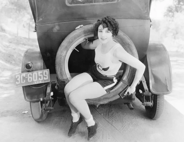 Молодая женщина, сидящая в дополнительном колесе автомобиля — стоковое фото