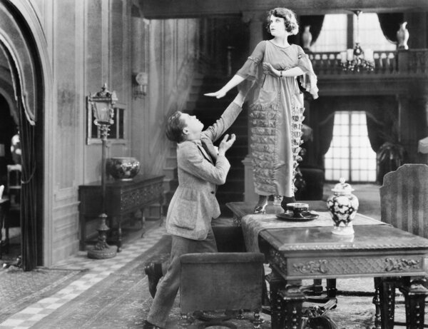 Woman standing on a table being adored by a man