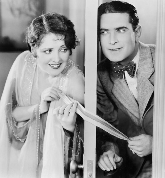 Пара флиртующих через слегка открытую дверь
