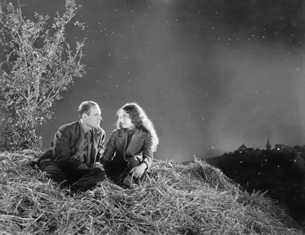 Romantikus pár ül egy boglya széna, a csillagok alatt — Stock Fotó