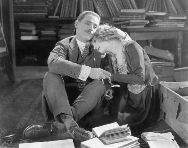 Casal sentado no chão de uma biblioteca segurando uns aos outros — Fotografia de Stock