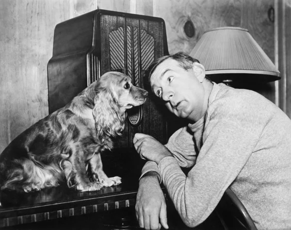 Mens en hond naar de radio luisteren — Stockfoto