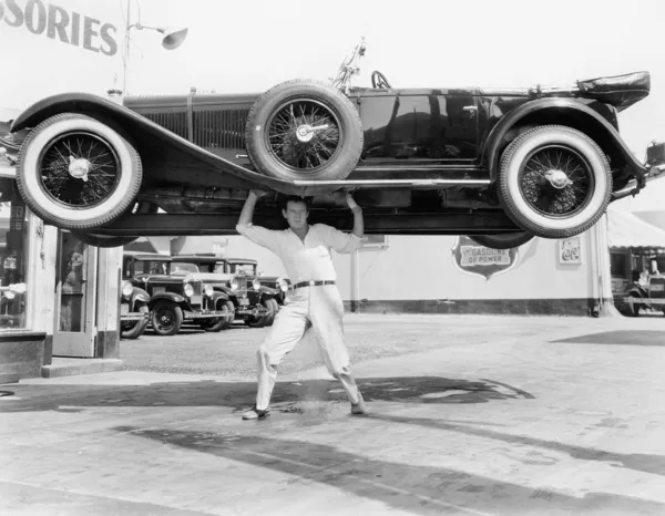Hombre fuerte levantando un coche sobre su cabeza — Foto de Stock