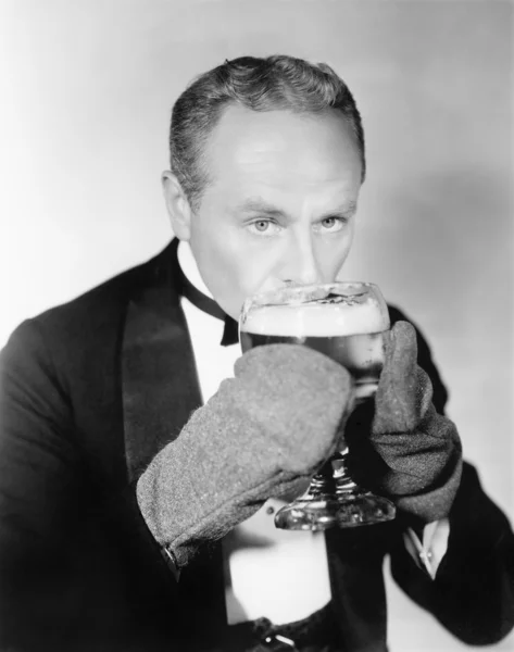 Uomo che beve un grande bicchiere di birra fredda con guanti — Foto Stock