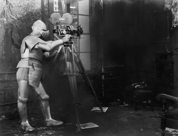 Caballero en el cine, un hombre con un traje blindado usa una cámara de cine —  Fotos de Stock