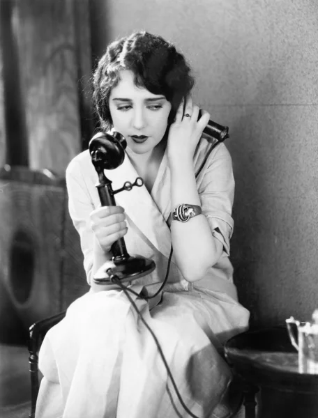 Jovem mulher sentada em uma cadeira segurando um telefone — Fotografia de Stock