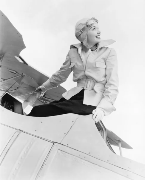 Mladá žena sedící na vrcholu dvojplošník s gargles a klobouk — Stock fotografie