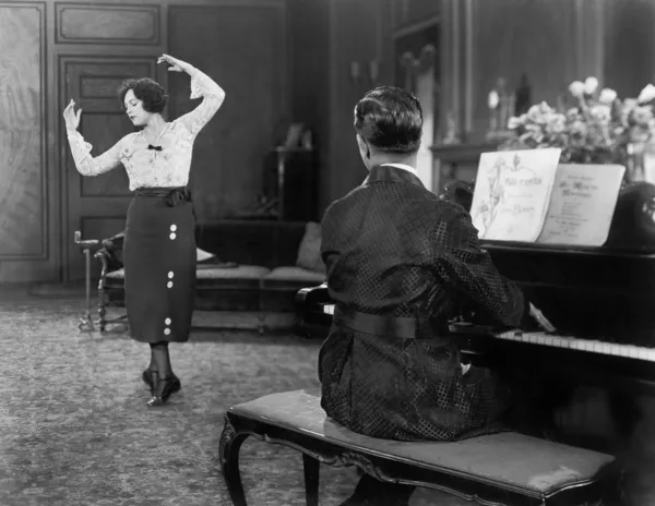 Kvinna dansar medan hennes man spelar piano — Stockfoto
