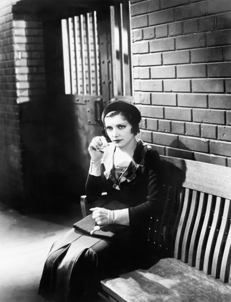 Mujer joven sentada en un banco frente a una celda — Foto de Stock