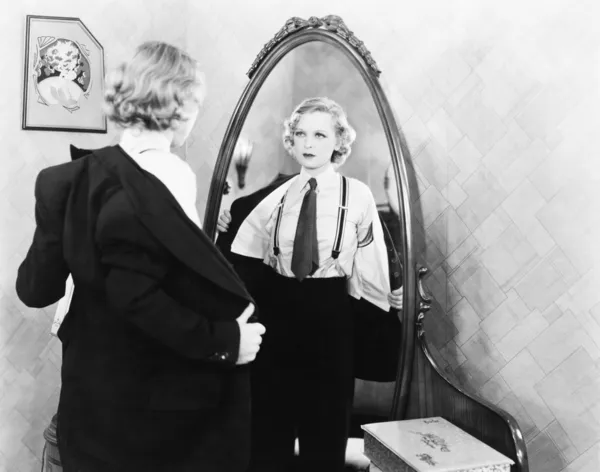 年轻女人在男人的衣服在镜子面前宽衣 — 图库照片