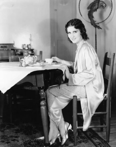 Mujer joven sentada en una mesa tomando té de desayuno —  Fotos de Stock