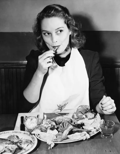 Mujer joven con babero comiendo langosta —  Fotos de Stock
