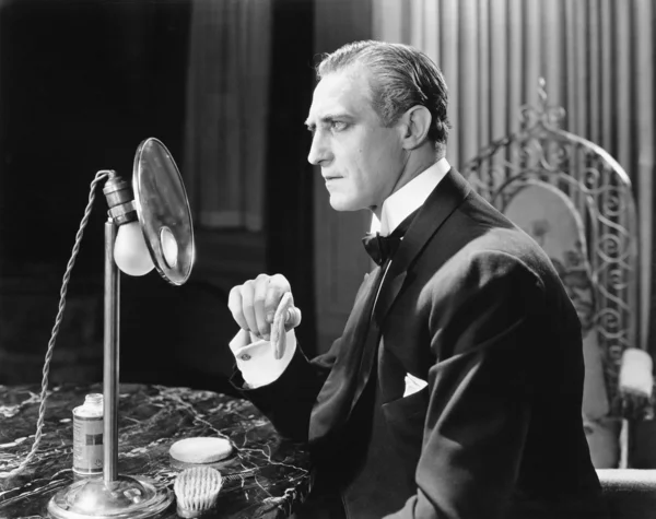 Homem colocando pó em seu rosto na frente de um espelho — Fotografia de Stock