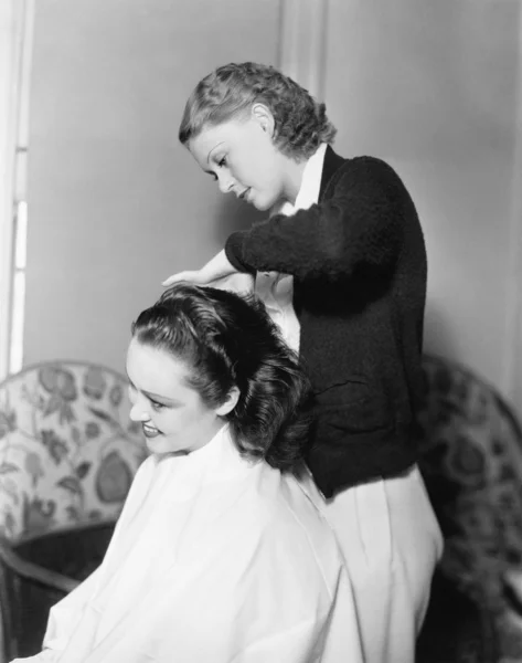 stock image One woman doing an other woman's hair