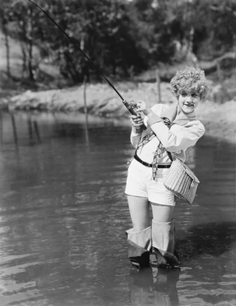 年轻女子穿涉禽类持有一根钓鱼竿 — 图库照片