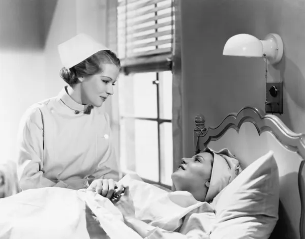 Krankenschwester tröstet eine Patientin im Krankenhausbett und spricht miteinander — Stockfoto
