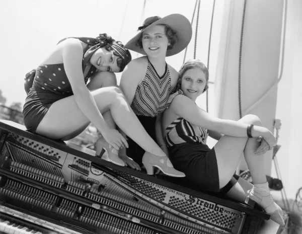 Tre kvinnor sitter på toppen av ett piano — Stockfoto