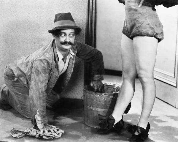 Άνθρωπος καθαρισμό του πατώματος, εξετάζοντας τα πόδια του μια γυναίκα — Φωτογραφία Αρχείου