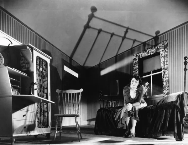 Jovem mulher sentada em um quarto parecendo assustada — Fotografia de Stock