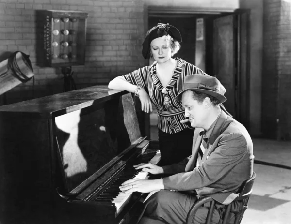 Мужчина играет на пианино, пока женщина слушает — стоковое фото